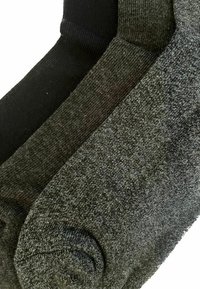 Drei Paar gefaltete Socken aus schwarzem, dunkelgrauem und hellgrauem Strickstoff, nebeneinander angeordnet.