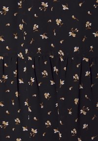 Schwarzer Stoff mit kleinen weißen und goldenen Blumenmustern, der eine geraffte Naht für Textur und ein weiches, fließendes Design aufweist.