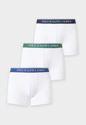 Junger Mann, barfuß stehend, trägt weiße Boxershorts mit dunkelgrünem Bund und Polo Ralph Lauren-Logo.