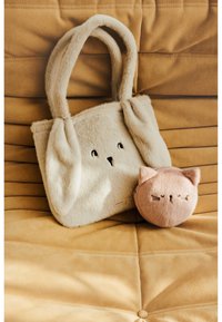 Pūkains beigs tote ar truša iezīmēm, garām ausīm un sejas izšuvumu, kopā ar apaļu gaiši rozā maisiņu, kas līdzinās kaķa sejai.