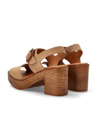 Sandalias de tacón de ante beige con un tacón grueso de textura de madera, punta abierta y diseño de tiras entrecruzadas con detalle de hebilla.