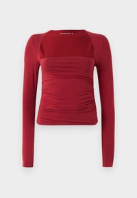 Top rosso fitted a maniche lunghe con scollatura quadrata e leggere arricciature in vita, presentato su uno sfondo chiaro e semplice.