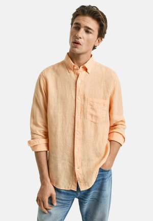 Helles orange Leinenhemd mit einem Button-Down-Kragen, verstellbaren Manschetten und einer Brusttasche, kombiniert mit hellblauen Jeans.