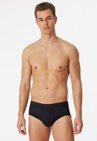 Culottes noires pour hommes avec une texture lisse, une taille élastique et une coupe ajustée. Aucun motif ou accent supplémentaire visible.