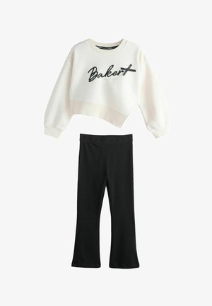 Hvid cropped sweatshirt med "Baker" tekst og sort sløjfedetalje, kombineret med sorte vidde bukser med elastisk talje.