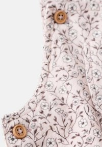 Tissu rose clair avec un motif floral, présentant de petites fleurs blanches et des accents marron. Deux boutons ronds en bois attachés sur le côté.