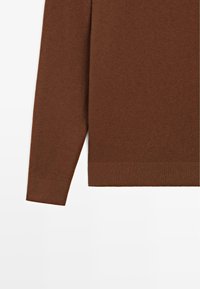 Hnědý pletený svetr s dlouhými rukávy, žebrovanými manžetami a lemem, s jemnou texturou a jednobarevným vzhledem bez vzorů či akcentů.