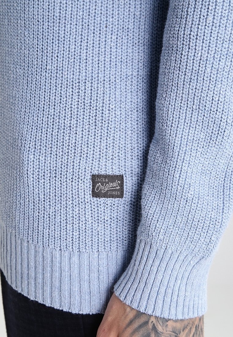 Jasnoniebieski sweter wełniany o fakturowanej tkaninie, ze ściągaczami na mankietach oraz prostokątną metką z napisem "Jack & Jones" w czerni i bieli.