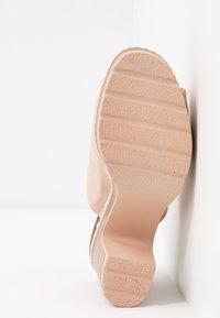 Semelle de chaussure couleur chair avec une surface texturée en caoutchouc. Présente un talon arrondi et un bord courbé près du talon pour le soutien et la stabilité.