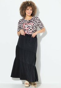 Camicia a maniche corte con stampa leopardata abbinata a una gonna maxi nera a balze. La gonna presenta una vita elasticizzata e una coulisse, con una texture liscia.