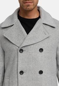 Grijze wollen blend peacoat met een dubbelzijdig ontwerp, brede revers en twee zwarte knopen. Haringbone patroon en zijzakken.