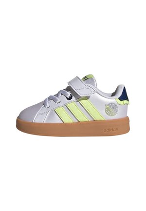 Bílá teniska Adidas se světle zelenými pruhy, gumovou podrážkou, páskem na suchý zip, šňůrkami a kruhovým logem na boku u paty.