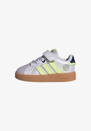 Hvid Adidas-sneaker med lysegrønne striber, gummisål, velcrolukning, snørebånd og en cirkulær logo på siden nær hælen.