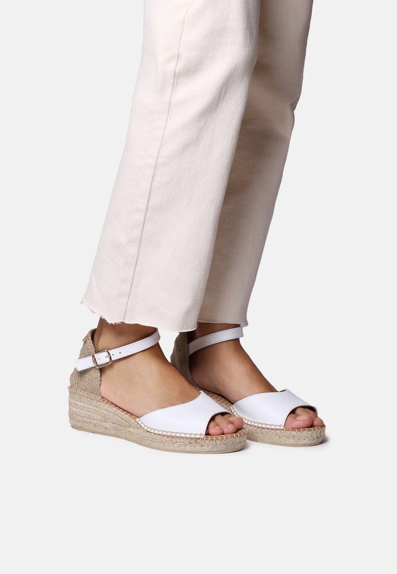 Valged nahast espadrillid sandaalid, millel on kootud jute-voodi ja kanna rihm. Disainis on avatud varvas ja lihtne, minimalistik stiil.