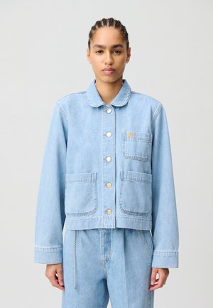 Veste en denim bleu clair avec un col, fermeture à boutons sur le devant, deux poches plaquées et un logo sur la poitrine.