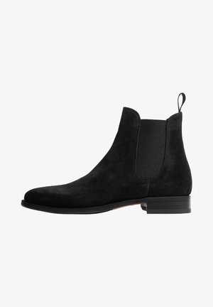 Stivale Chelsea in suede nero con pannelli elastici laterali, punta rotonda e linguetta sul retro. Presenta un tacco basso impilato.