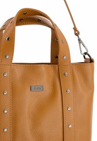 Bruine leren handtas met een textuurafwerking, voorzien van zilveren studs, dubbele bovenhandgrepen en een afneembare schouderriem. Inclusief zilveren logo accent.
