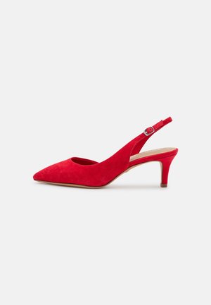 Czerwony zamszowy but na obcasie typu slingback z szpiczastym noskiem, regulowanym paskiem z klamrą i niskim obcasem typu szpilka na białym tle.