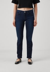 Tummansiniset skinny-farkut, joissa on keskitason vyötärö, nappikiinnitys ja kaksi etutaskua. Sujuva, joustava denimkangas puhtaalla viimeistelyllä.