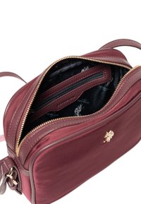 Borsa a tracolla in pelle bordeaux con cerniera dorata, dotata di interno foderato, scomparto con zip e dettaglio con logo sul davanti.
