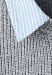 Grauer gestrickter Stoff mit vertikaler Ripptextur, versehen mit einem hellblauen Kragen mit weißen Streifen. Weiche Textur, Nahaufnahme.