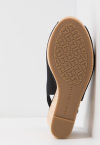 Sandal in tessuto nero con suola in gomma tan testurizzata, caratterizzata da un motivo geometrico e dettagli del marchio. Design con ritagli laterali.