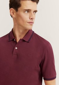 Polo bordeaux con colletto a righe navy, patta con due bottoni e logo ricamato in modo discreto sul petto. Materiale in comoda miscela di cotone.
