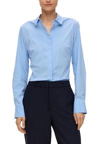 Helle blaue Button-Down-Bluse mit langen Ärmeln und weicher Textur. Verfügt über einen klassischen Kragen und einen geraden Saum, kombiniert mit dunklen Hosen.