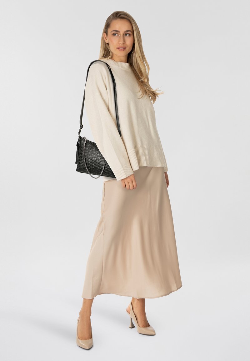 Suéter de punto beige con dobladillo acanalado, combinado con una falda midi beige lisa y tacones altos beige. Bolso negro acolchado con correa de cadena.