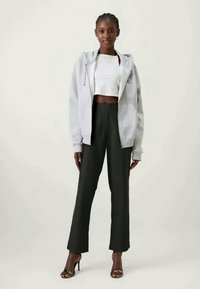 Γκρι υπερμεγέθη φούτερ, λευκή κοντομάνικη μπλούζα, μαύρα φαρδιά παντελόνια και ψηλοτάκουνα σανδάλια. Λείο ύφασμα, άνετη εφαρμογή, διακριτές υφές και γραμμές.