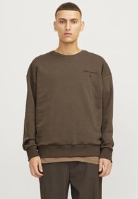 Sudadera de algodón marrón con un corte relajado, puños y dobladillo de canalé, con texto bordado en negro en el pecho y un diseño minimalista.