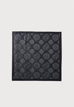 Black square scarf with repeating white geometric and circular patterns and small dot clusters, branded "GUESS" on the edges.