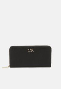 Melnas ādas maks ar gludu tekstūru, kuru rotā zelta "CK" logos un kas aizveras ar rāvējslēdzēju. Kompakta taisnstūra forma bez rakstiem.