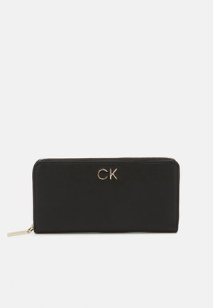 Sort læderpung med en glat tekstur, der har et gyldent "CK" logo og en lynlåslukning. Kompakt, rektangulær form uden mønstre.