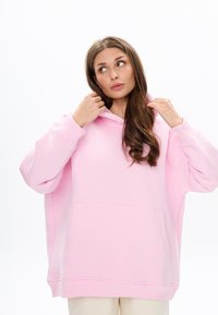 Oversized roze hoodie van zachte stof, met een voormouwzak, een trekkoord capuchon en geribde manchetten, met een gladde textuur.
