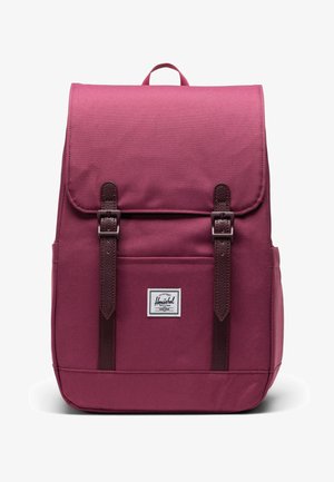 Maroon backpack made of durable fabric, featuring a fold-over flap, brown leather straps, and a logo patch at the front. Rectangular shape.