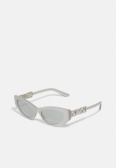 Gafas de sol con forma de ojos de gato en color gris y acabado mate, con lentes verdes y accesorios metálicos dorados en las patillas con acentos geométricos.