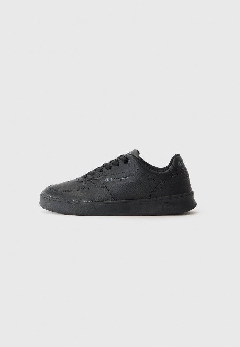 Chaussure de sport noire au design épuré avec un dessus en synthétique lisse, semelle en caoutchouc plate, bout rond et fermeture à lacets avec détail de logo sur le côté.