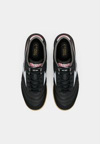 Pantofi sport negri cu un exterior din piele netedă, accente albe și o talpă din cauciuc caramel. Dispune de șireturi și un guler căptușit pentru confort.