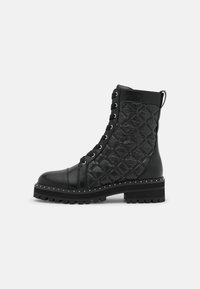 Botas negras hasta el tobillo con un empeine de cuero texturizado, diseño acolchado en los laterales, ojales de metal y una suela gruesa con tachuelas.