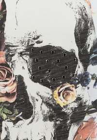 Schwarz-weiße Totenkopf-Grafik mit bunten Rosen und Nieten, die im Bereich der Stirn eingearbeitet sind, auf einem Stoffhintergrund.