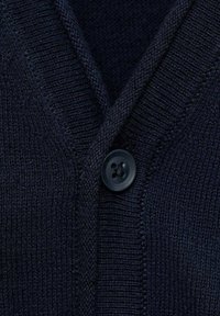 Námořnický pletený cardigan se vzorem do V, texturovanou tkaninou a kulatým černým knoflíkem u zapínání.