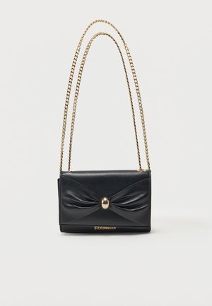 Sac d'épaule en cuir noir avec bandoulière en chaîne dorée, détail plissé à l'avant, fermoir ovale en or et logo "Steve Madden" sur le bord inférieur.