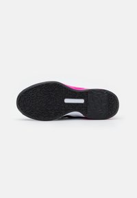 Suela de zapato de goma negra con un patrón texturizado, con acentos en rosa brillante y una pequeña sección de logo en blanco.