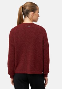 Bordowy sweter o fakturowanym wykończeniu, luźnym kroju i okrągłym dekolcie. Charakteryzuje się widocznymi przeszyciami oraz małym logo na plecach.