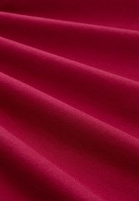 Tiefmagenta-Stoff mit glatter Textur, der weiche, subtile Falten aufweist und eine einheitliche Farbe aufweist. Keine Muster oder Akzente sichtbar.