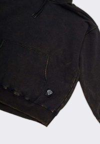 Zwarte hoodie met een kangoeroezak, voorzien van een klein logopatchje aan de onderkant links. De stof heeft een subtiele verweerde textuur en afwerking.