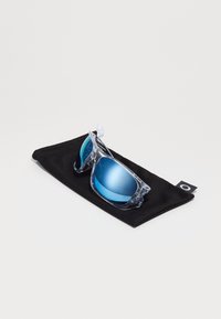 Okulary przeciwsłoneczne z przezroczystą plastikową ramką i niebieskimi lustrzanymi soczewkami, umieszczone na czarnym miękkim etui. Charakteryzują się eleganckim designem i wyraźnym kolorem soczewek.