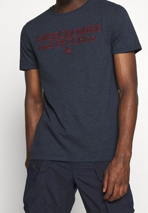 Marineblaues Baumwoll-T-Shirt mit kurzen Ärmeln, auf dem "ABERCROMBIE and FITCH co." in roter Schrift steht, ergänzt durch ein kleines Logo über dem Text.