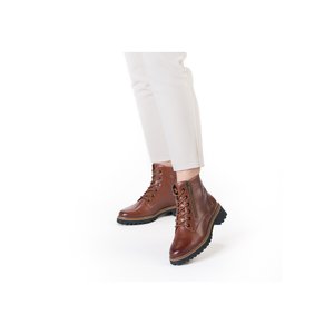 Brown leather lace-up ankle boots with side zippers worn with white cropped pants against white background.